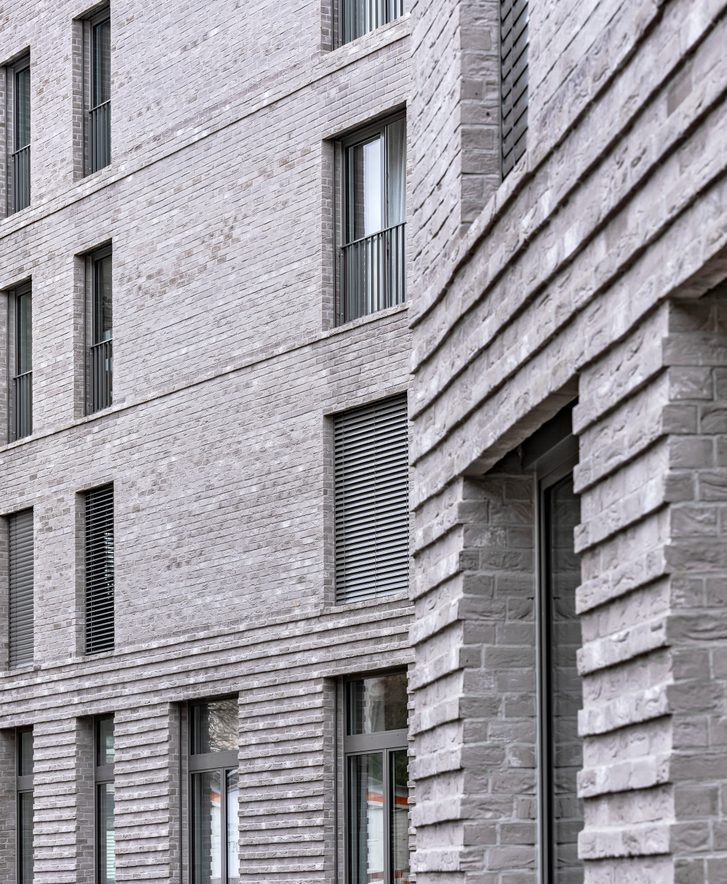 Moderne Fassade aus grauem Backstein mit mehreren Fenstern