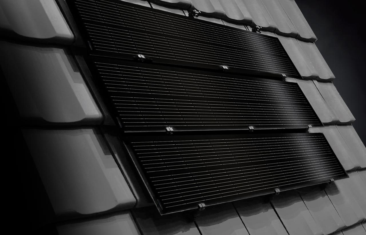 Schwarze Solarpanels auf einem grauen Ziegeldach bei schwacher Beleuchtung