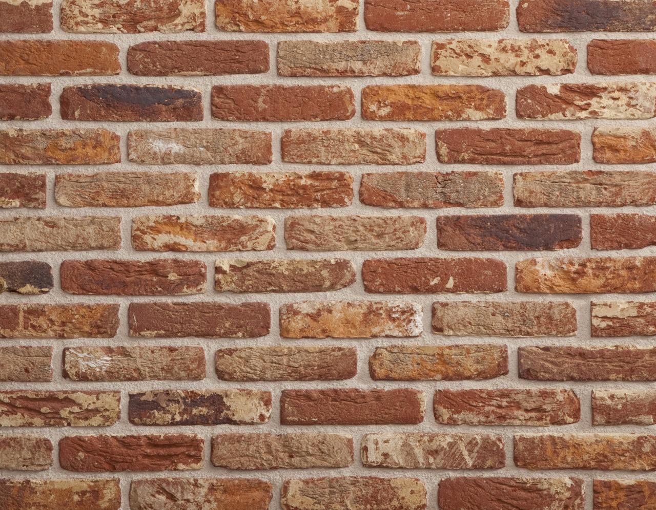 Rote Backsteinmauer mit unregelmaessigen Fugen und unterschiedlichen Farbtoenen