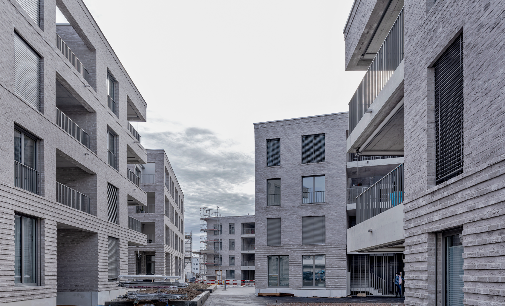 Moderne Wohnhaeuser aus Grau mit Balkonen in einem Neubauviertel bei bewolktem Himmel