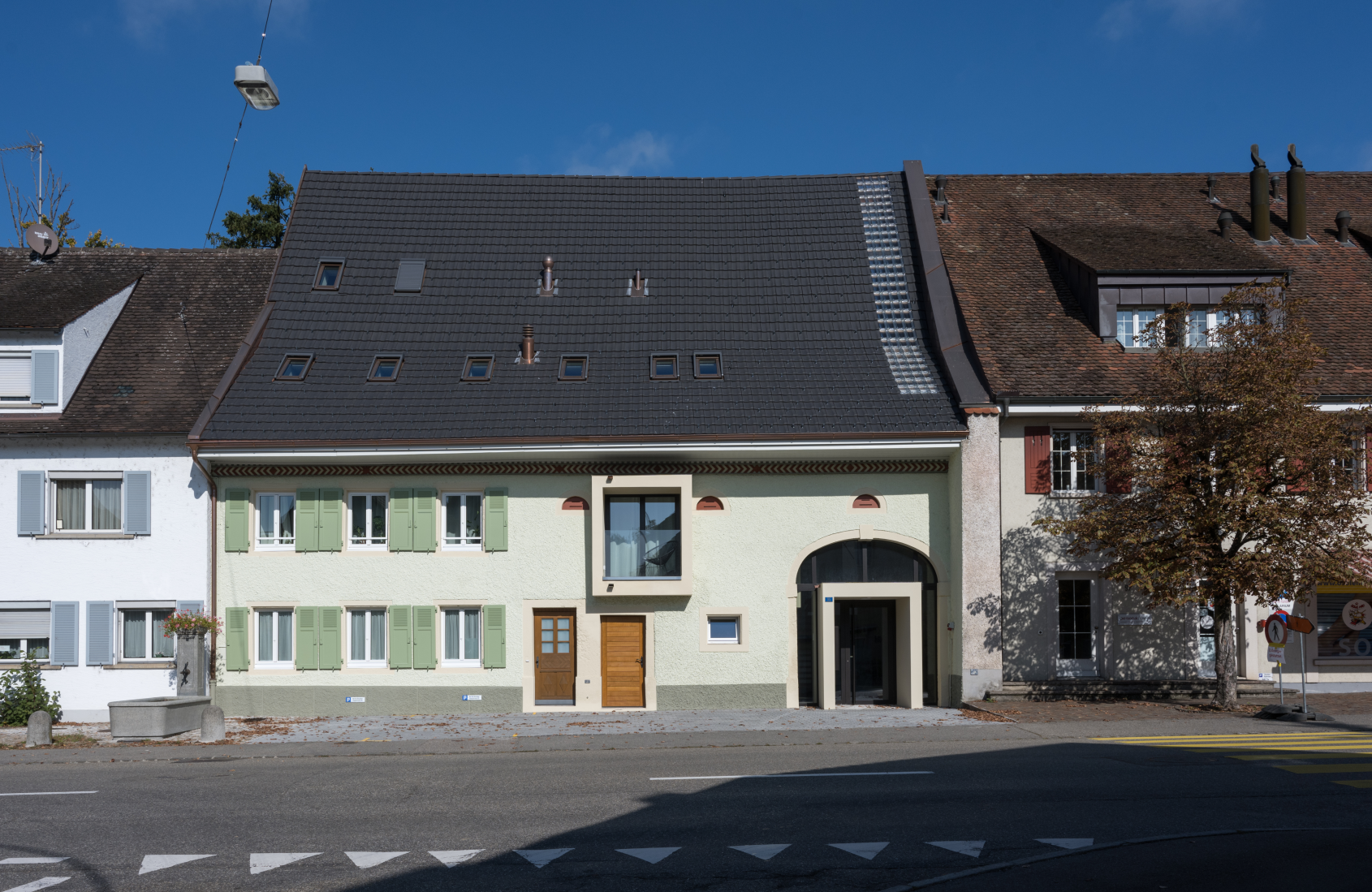 Helle Wohnhaeuser mit dunklen Daechern an einer sonnigen Strasse